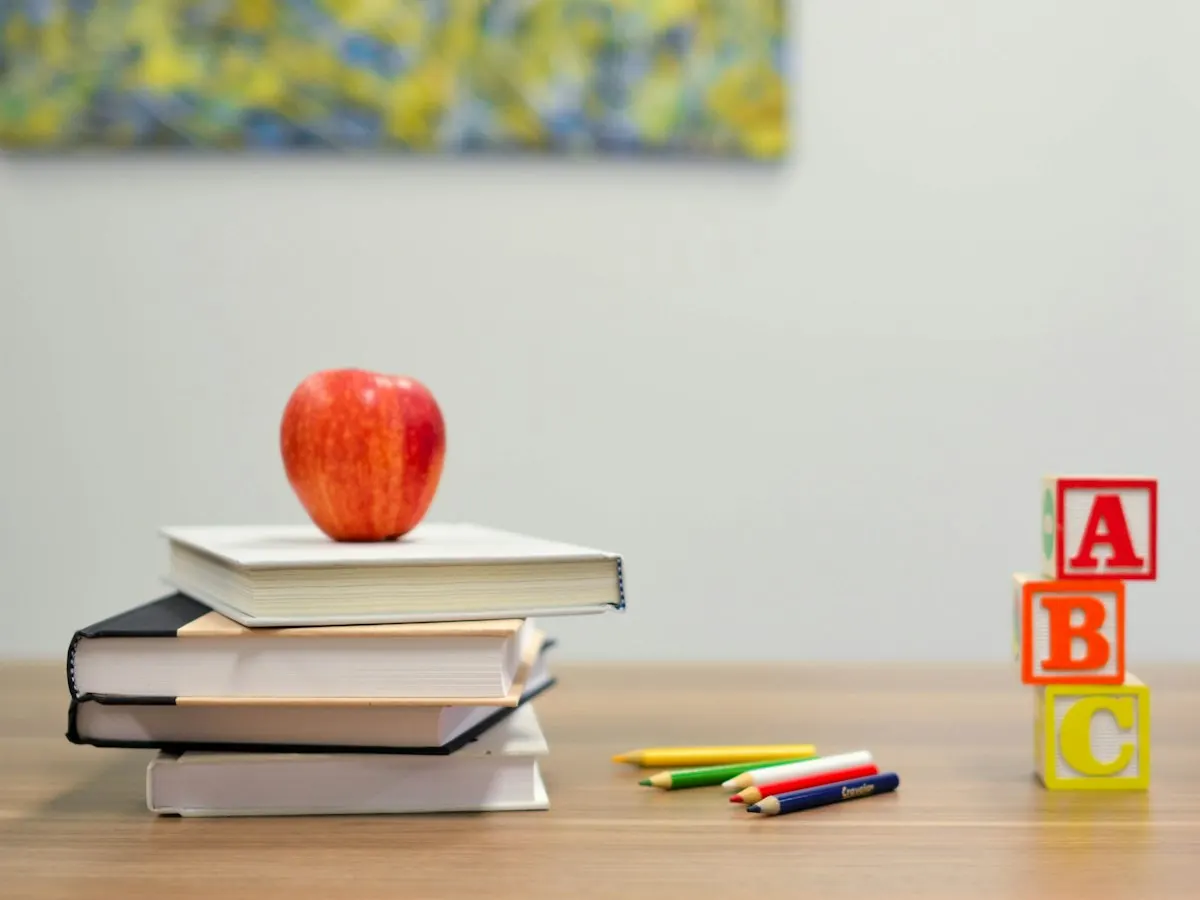 Stapel boeken met een appel op een bureau