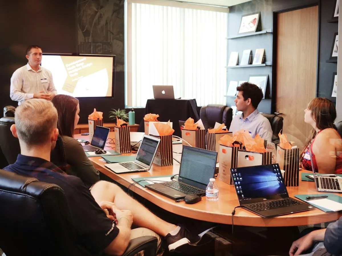Een team zit rond een vergadertafel met laptops tijdens een overleg
